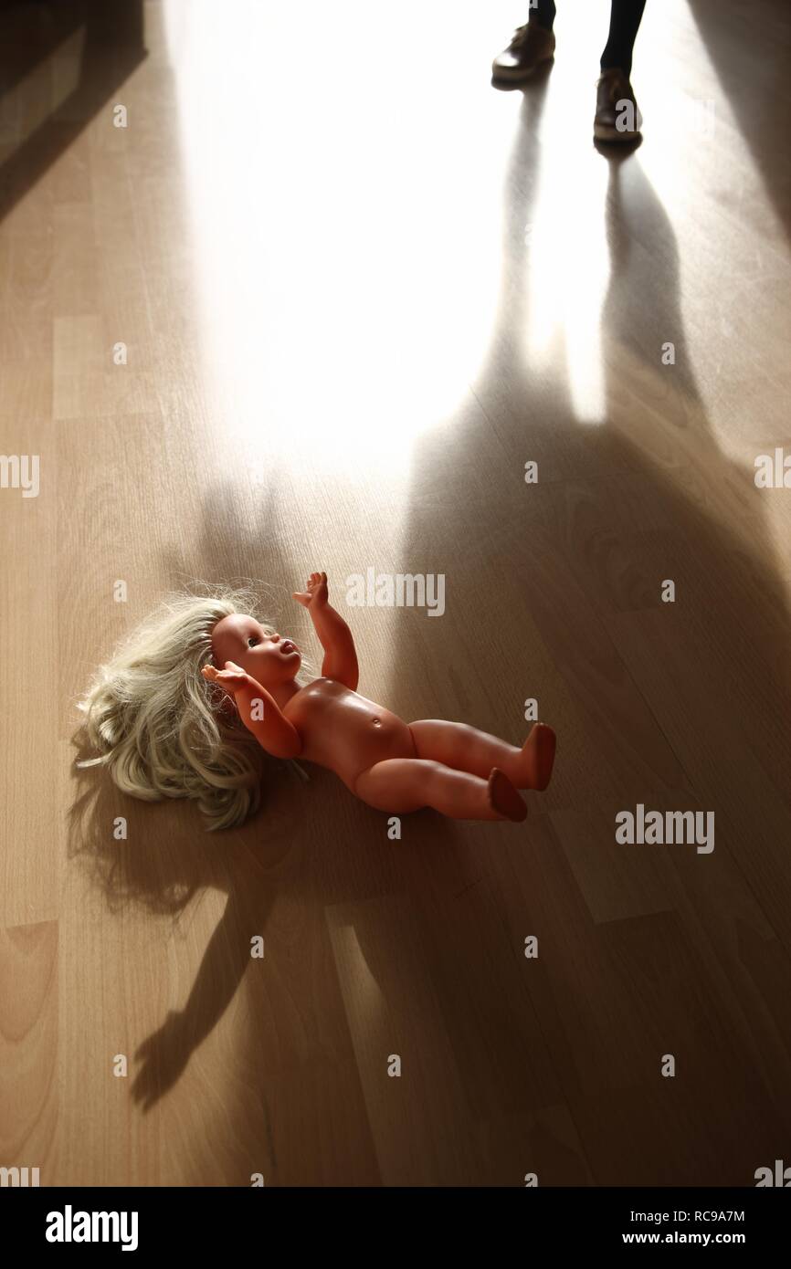 Doll lying on the floor, symbolic image for child abuse, violence against children Stock Photo