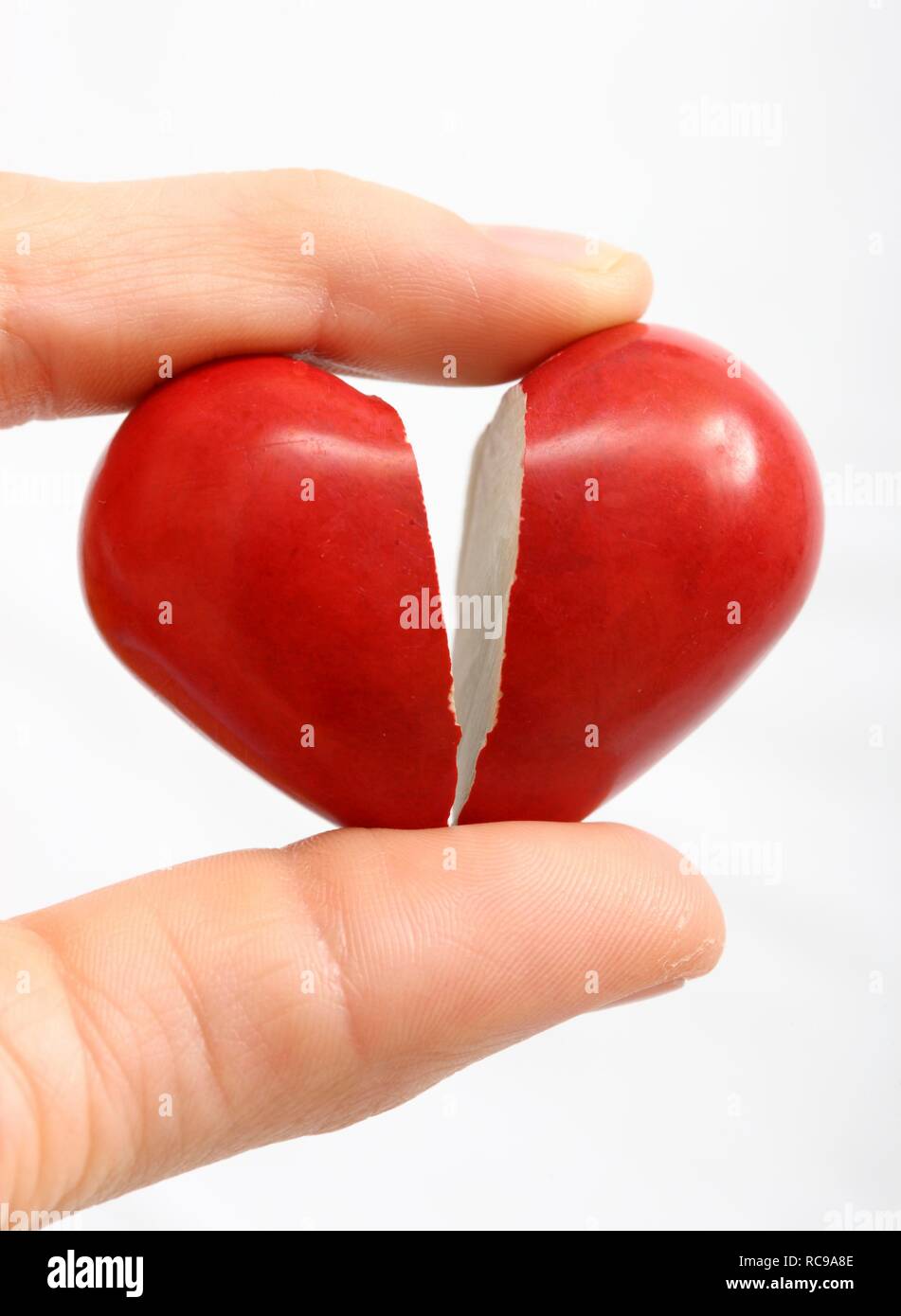 Hand holding a broken heart, symbolic image for heart disease, heart attack, a diseased heart, cardiology or heartache Stock Photo