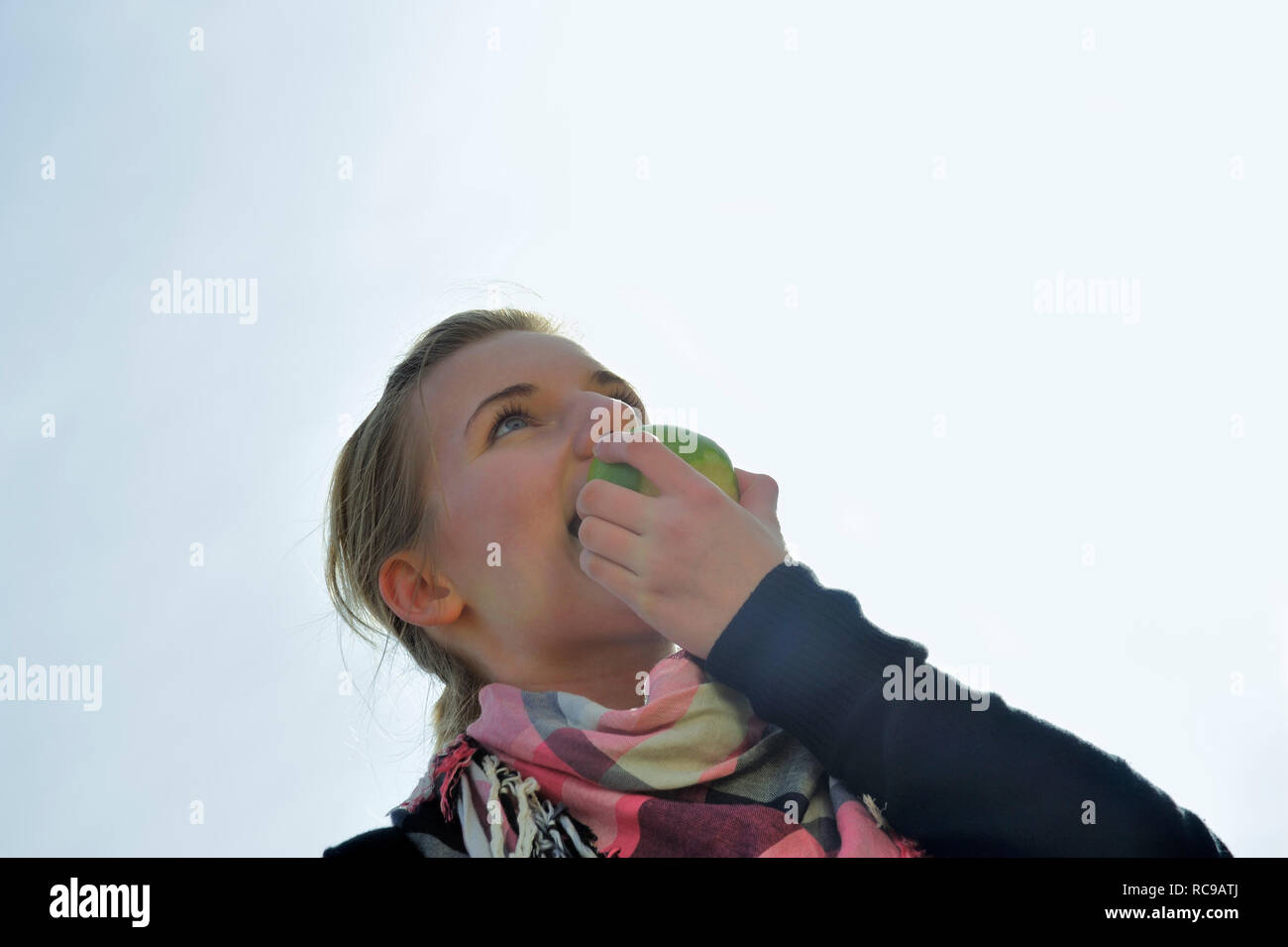 junge Frau beisst in einen grünen Apfel - in den sauren Apfel beissen | young woman eats a green apple - to swallow a bitter pill or to grasp the natt Stock Photo