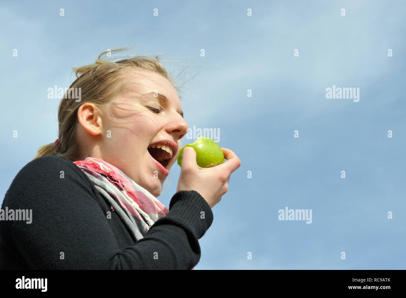 junge Frau beisst in einen grünen Apfel - in den sauren Apfel beissen |  young woman eats a green apple - to swallow a bitter pill or to grasp the  natt Stock Photo - Alamy