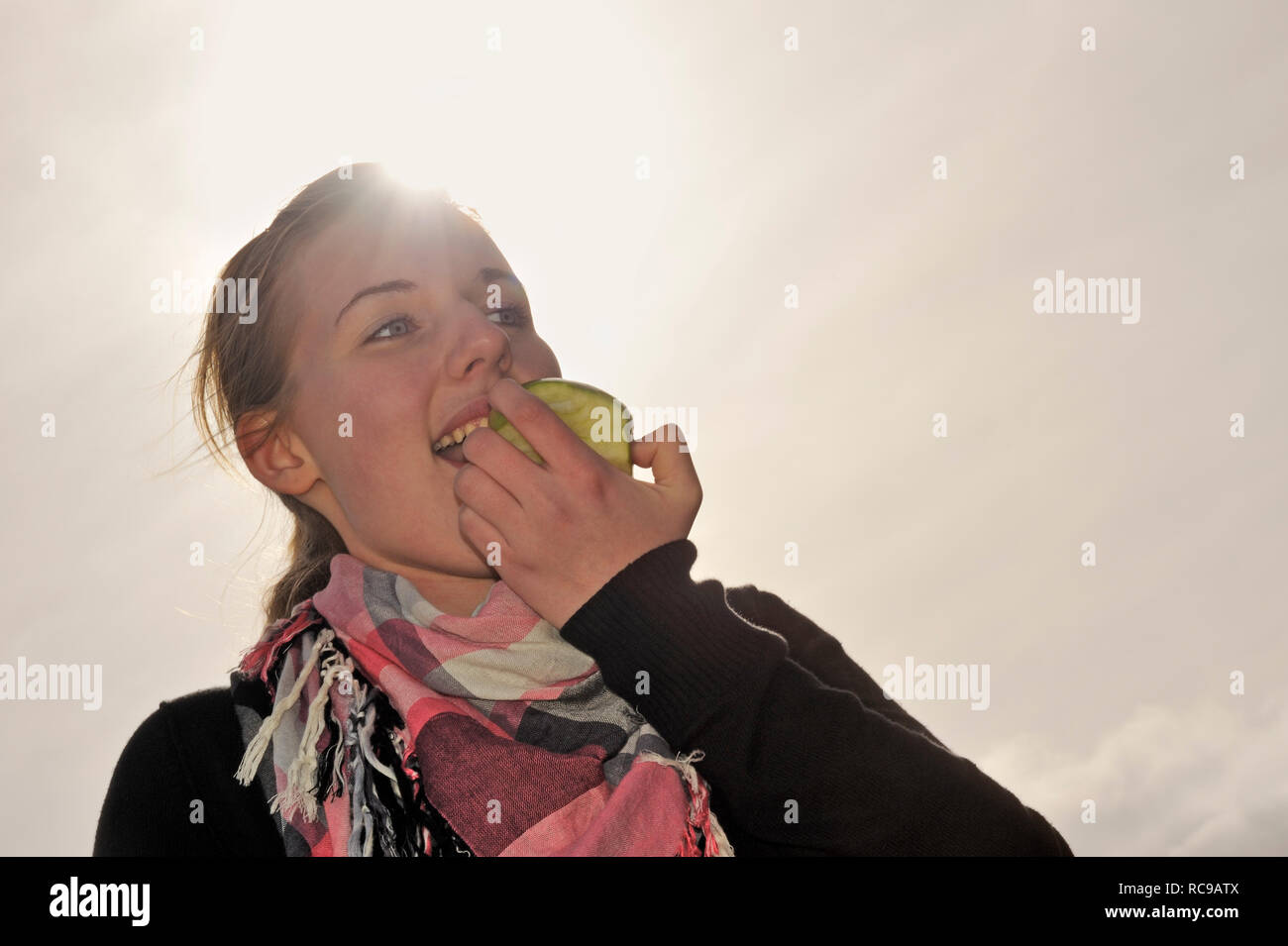 junge Frau beisst in einen grünen Apfel - in den sauren Apfel beissen | young woman eats a green apple - to swallow a bitter pill or to grasp the natt Stock Photo