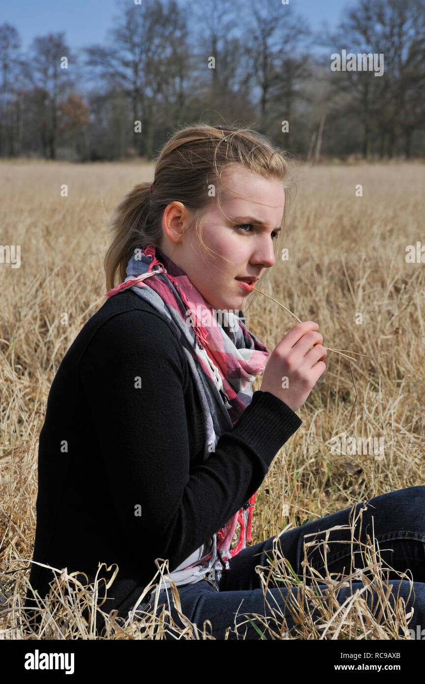 jugendliches Mädchen sitzt nachdenklich im Gras | young female teenager sitting outside in a dreamy mood Stock Photo