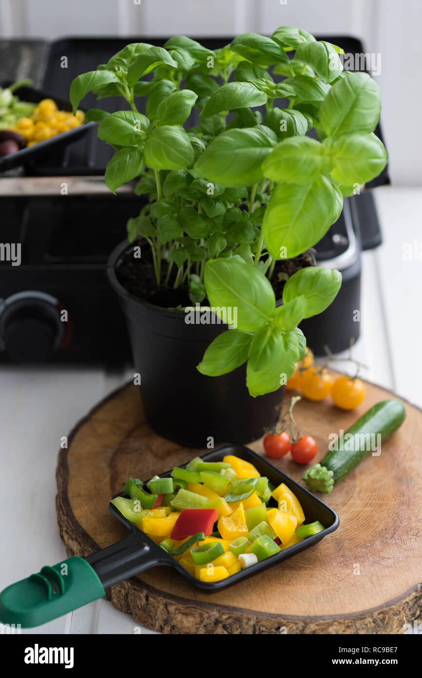 vegan raclette, raclette pan with finely chopped vegetables on a wooden