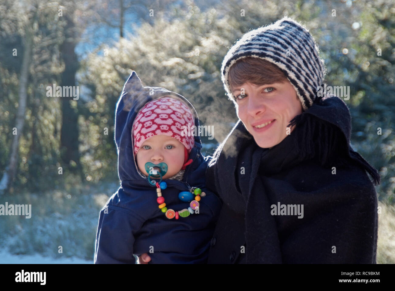 Mutter mit Baby im Arm, draußen Winter | mother carrying her baby on the arm, outside winter Stock Photo
