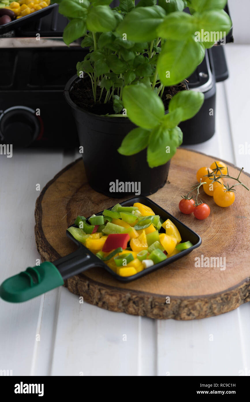 Vegan Raclette Raclette Pan With Finely Chopped Vegetables On A Wooden Board Next To Tomatoes And A Pot Of Basil Stock Photo Alamy