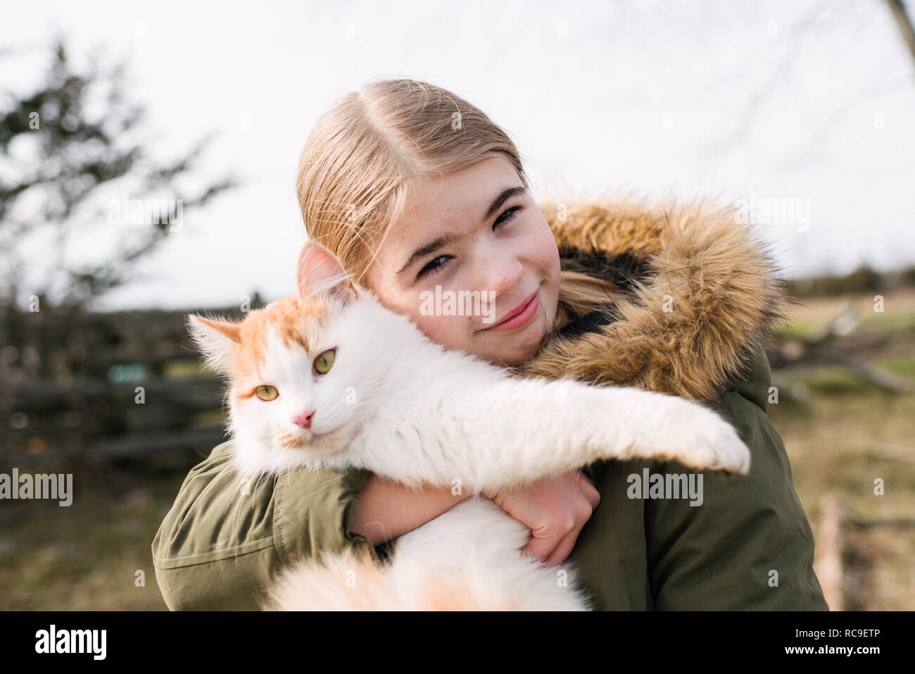 Girl cuddling cat in field Stock Photo