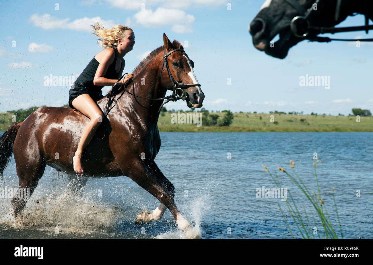 Woman riding horse across river Stock Photo