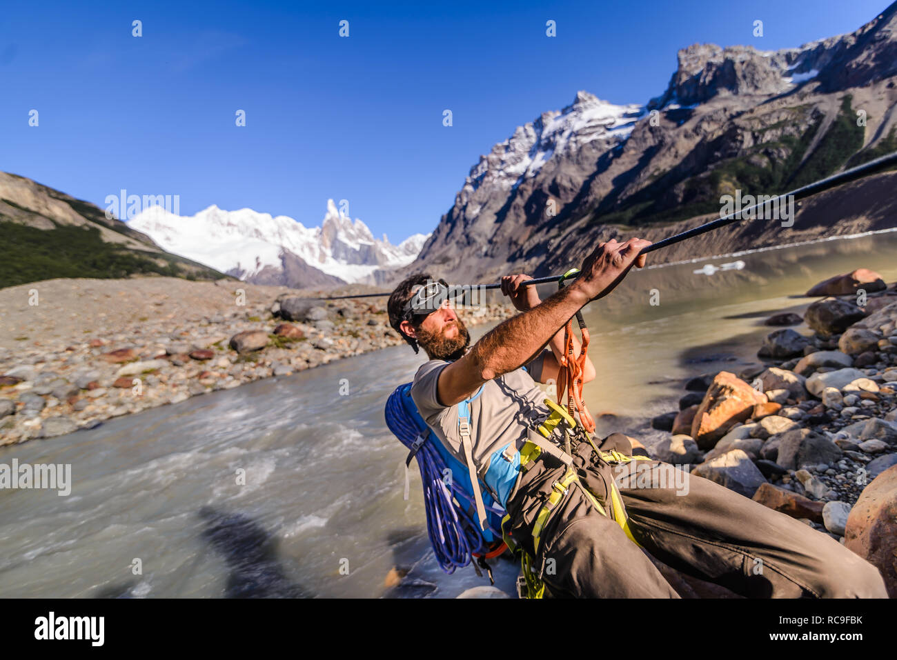 Rock climber sliding on rope over river, El Chaltén, south Patagonia, Argentina Stock Photo