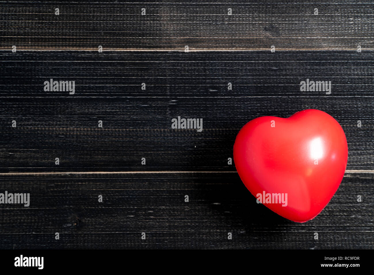 The red heart is placed on the left side of the black wood table. Copy ...