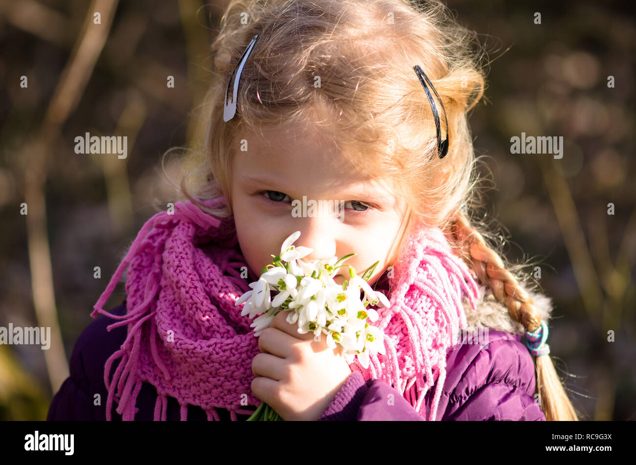 beautiful lovely girl smelling to white snowdrop flowers in her hand Stock Photo