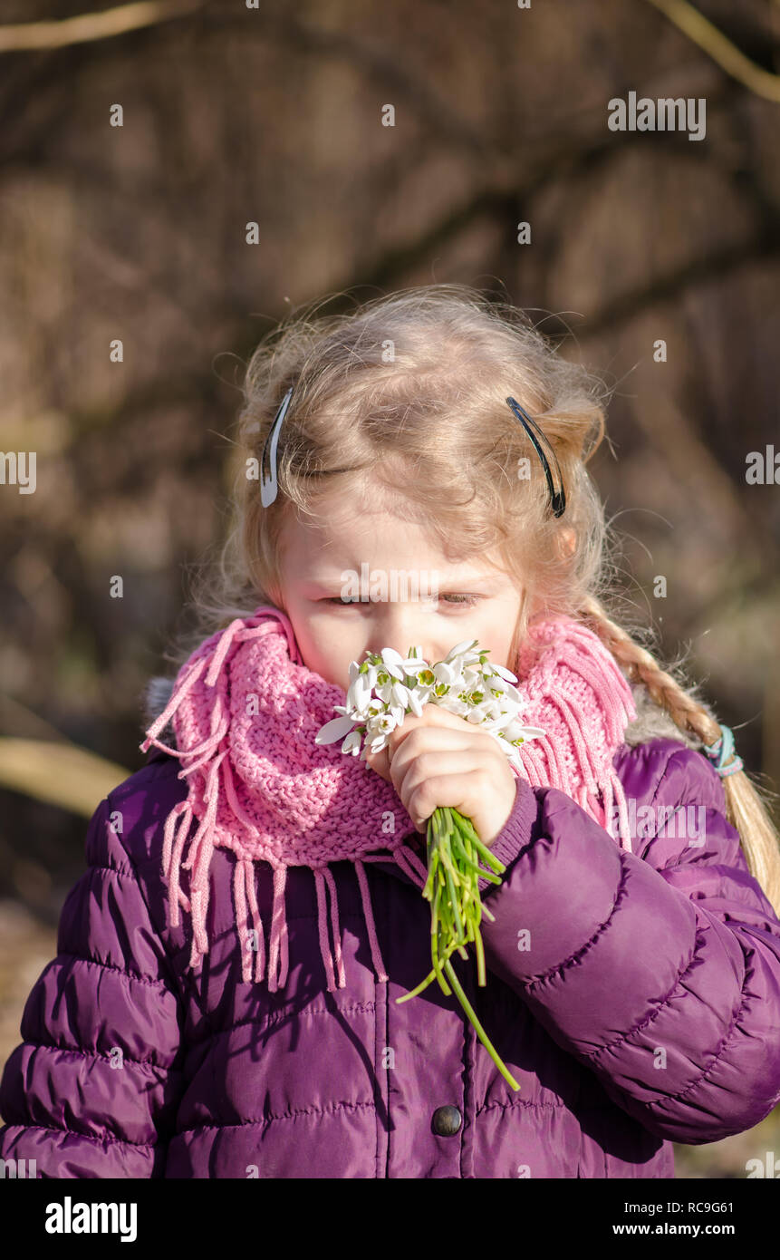 beautiful lovely girl smelling to white snowdrop flowers in her hand Stock Photo