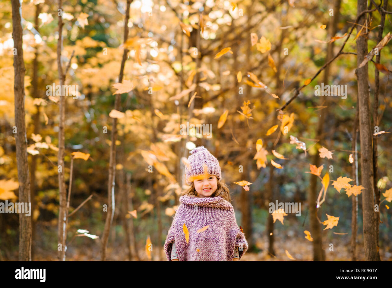 Falling autumn leaves in front of little girl in forest Stock Photo