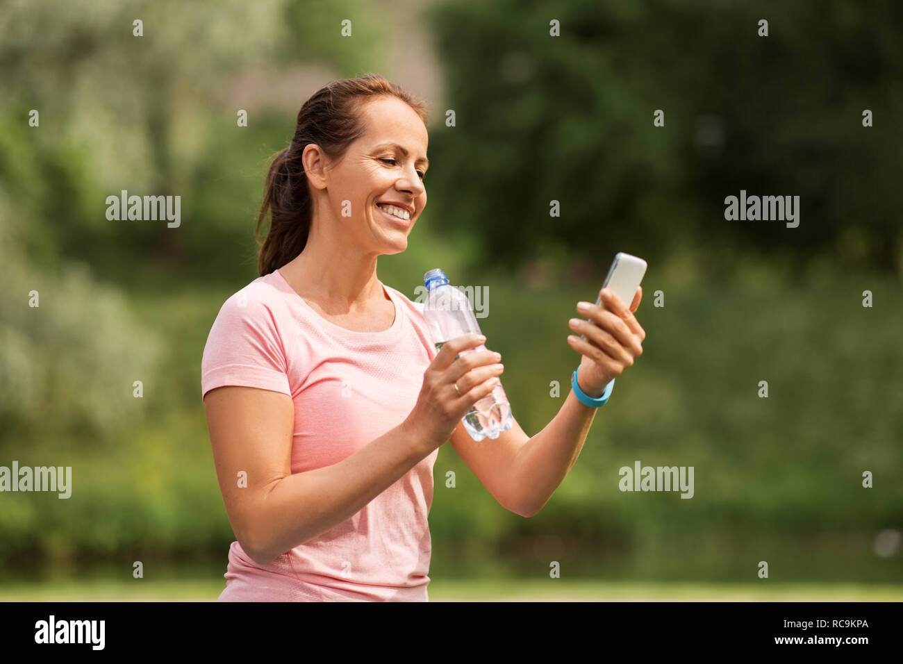 https://c8.alamy.com/comp/RC9KPA/woman-with-smartphone-drinking-water-in-park-RC9KPA.jpg