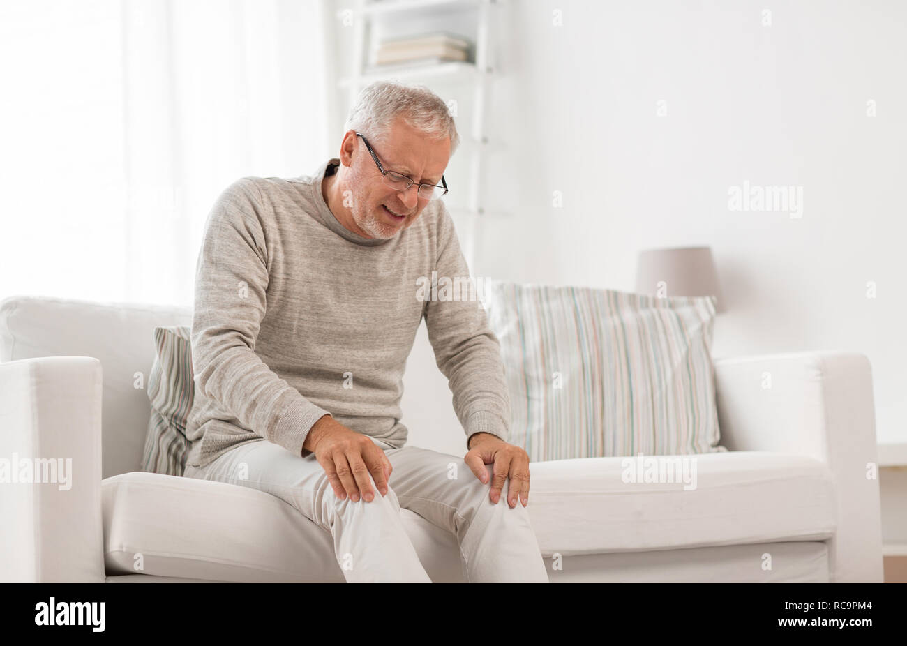 senior man suffering from knee ache at home Stock Photo - Alamy