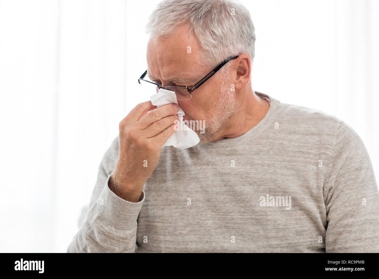 sick senior man with paper wipe blowing his nose Stock Photo