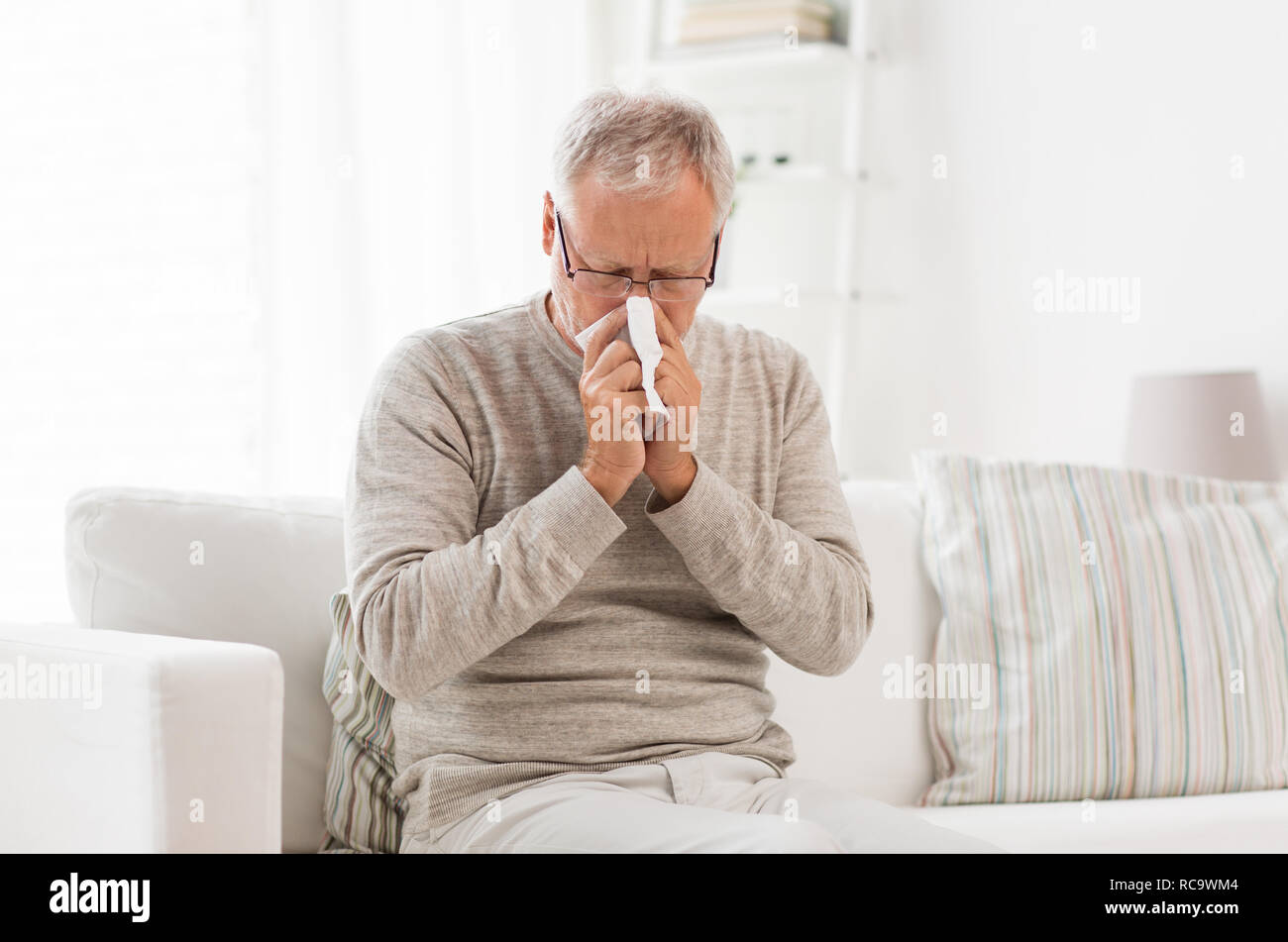sick senior man with paper wipe blowing his nose Stock Photo