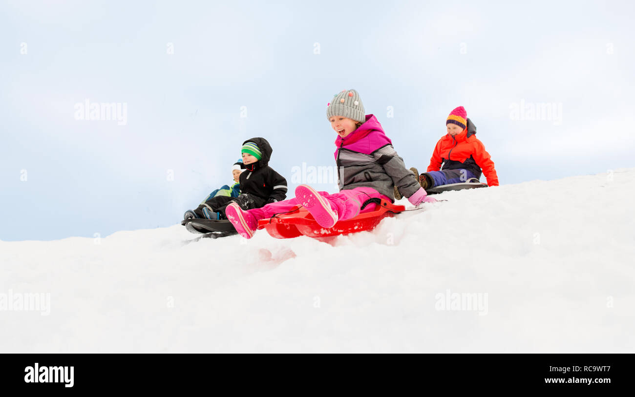 kids sliding on sleds down snow hill in winter Stock Photo Alamy