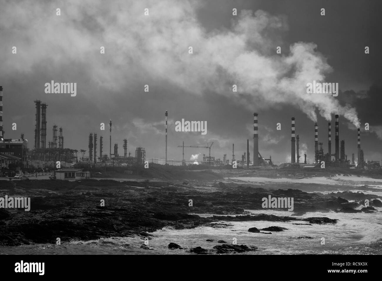 Oil refinery by the sea before rain and storm. Converted black and white. Stock Photo