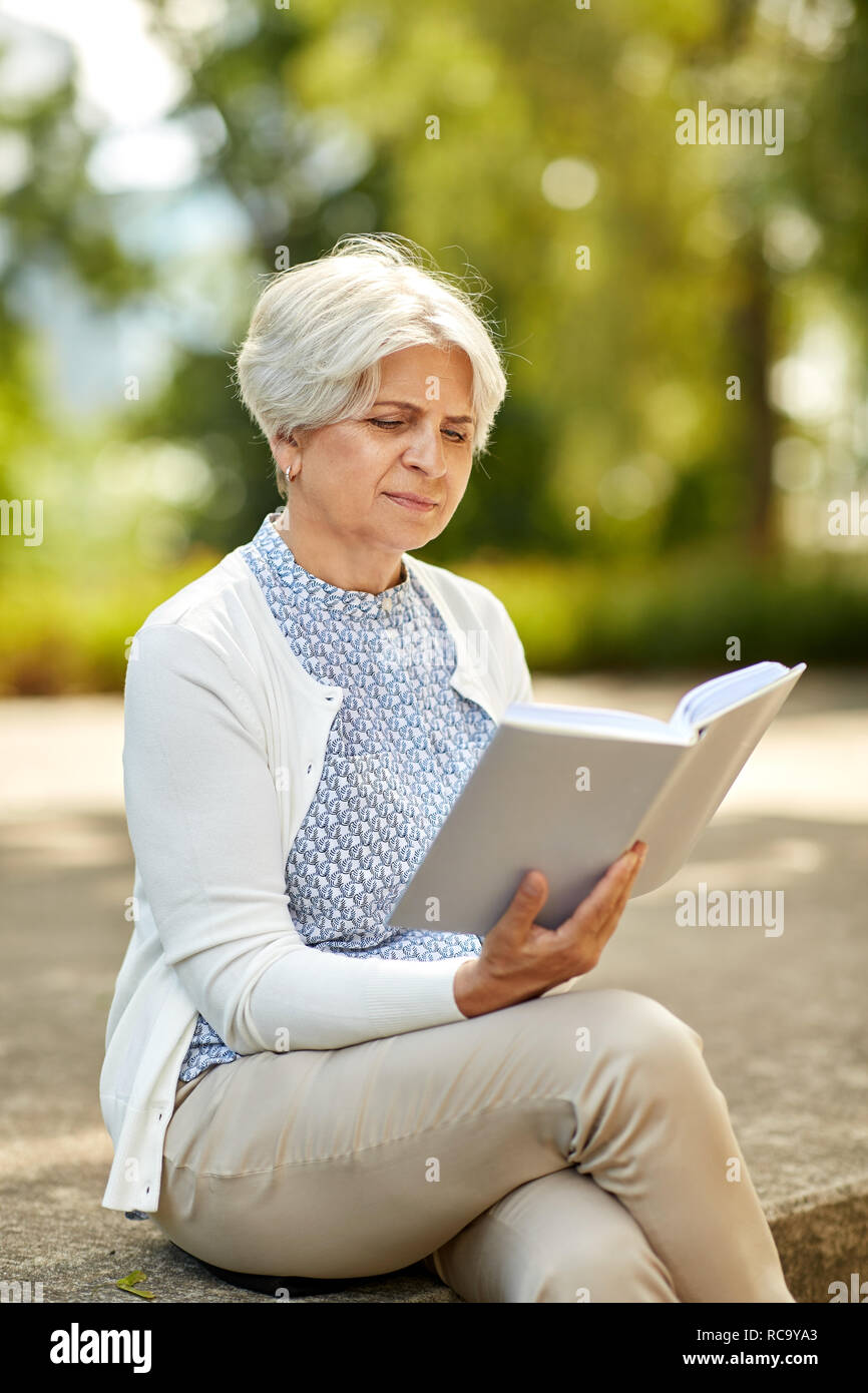 senior woman reading book at summer park Stock Photo