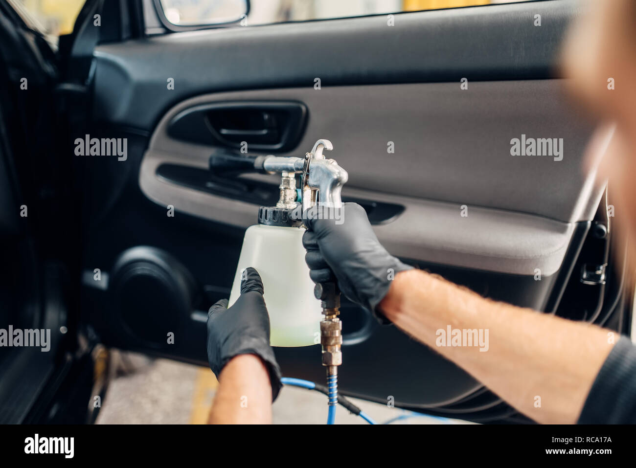 Carwash Service Male Worker In Gloves Using Special Spray