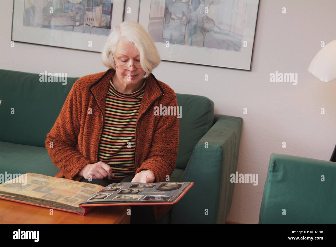 Frau mittleren Alters schaut sich Fotoalbum an  | middleaged woman is looking at photo album Stock Photo