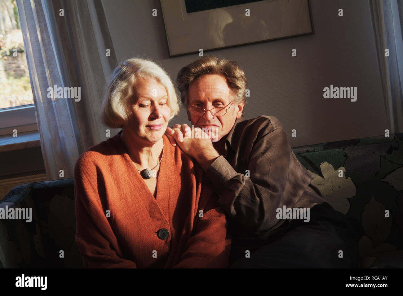 Pärchen mittleren Alters sitzt auf einem Sofa  | middleaged couple is sitting on a couch Stock Photo
