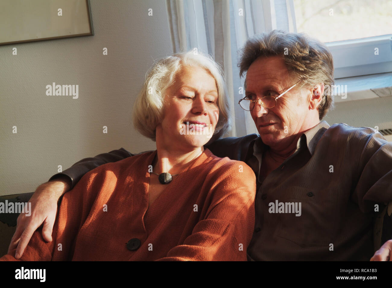 Pärchen mittleren Alters sitzt auf einem Sofa  | middleaged couple is sitting on a couch Stock Photo