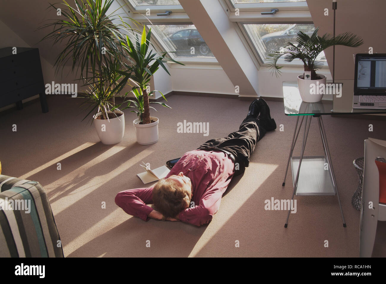 Mann mittleren Alters liegt auf dem Boden und entspannt | middleaged man is relaxing on the floor Stock Photo