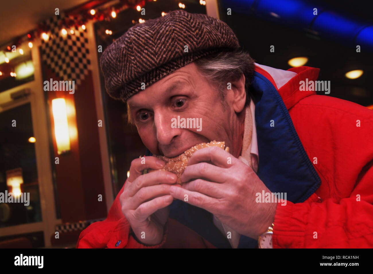 Mann mittleren Alters isst Hamburger | middleaged man eats hamburger Stock Photo