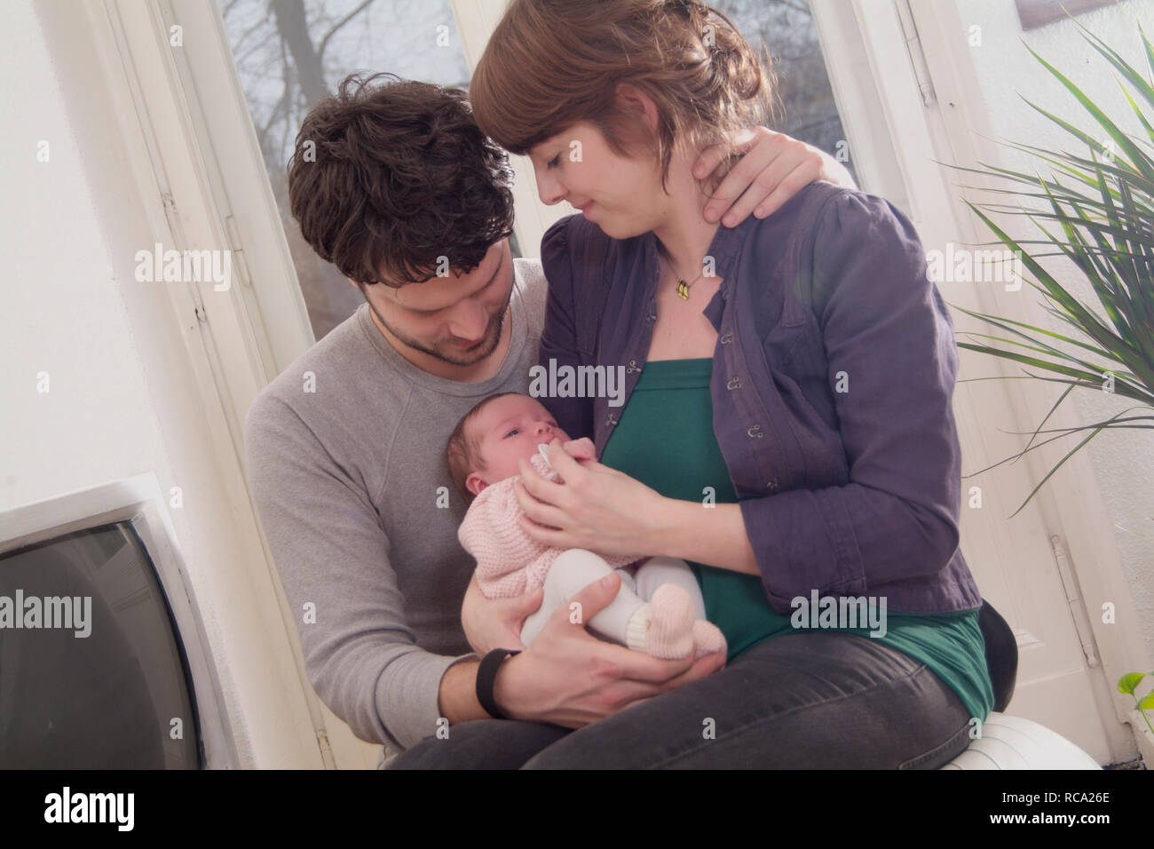 Junge Eltern halten ihre neugeborene Tochter im Arm, das Kind ist 12 Tage alt | young parents holding her new born baby in her arms - the baby ist 12 Stock Photo