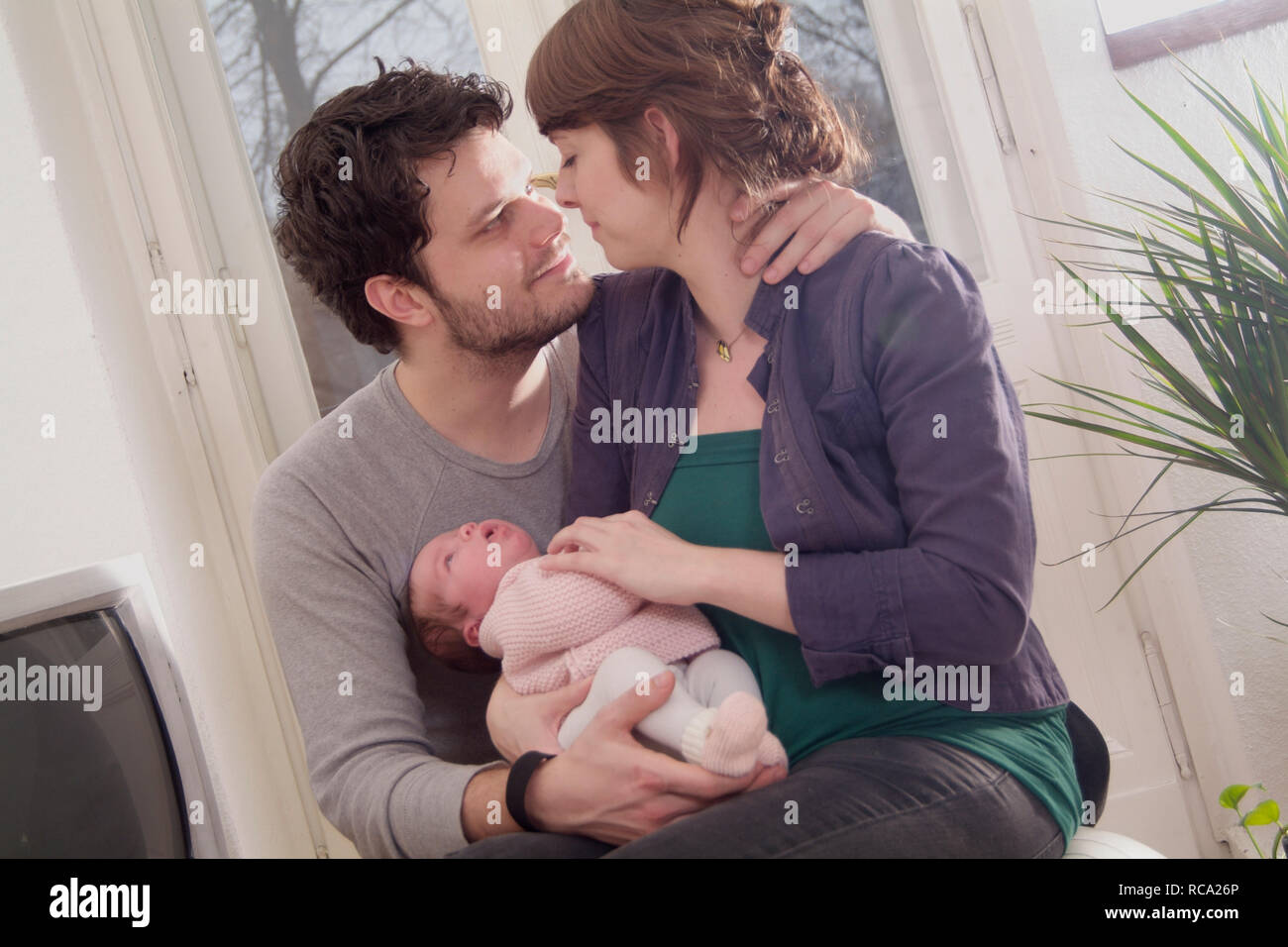 Junge Eltern halten ihre neugeborene Tochter im Arm, das Kind ist 12 Tage alt | young parents holding her new born baby in her arms - the baby ist 12 Stock Photo