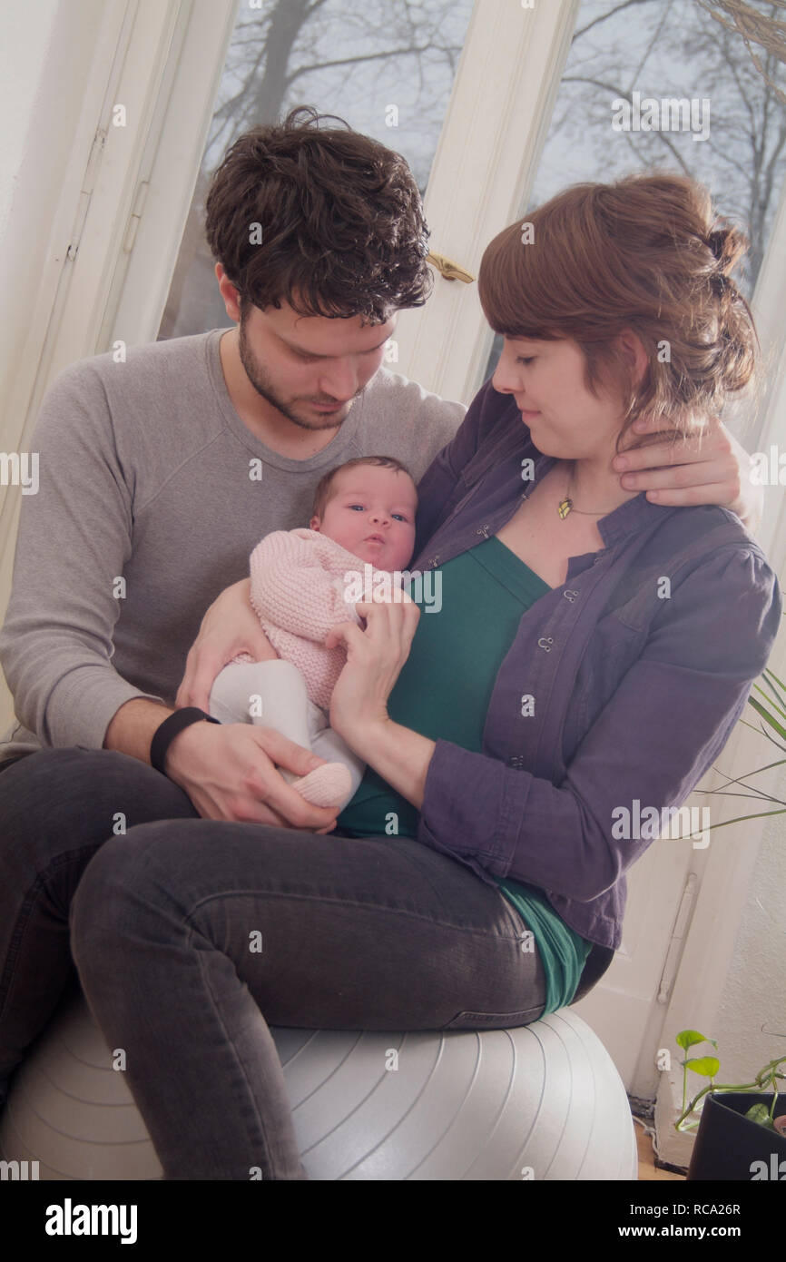 Junge Eltern halten ihre neugeborene Tochter im Arm, das Kind ist 12 Tage alt | young parents holding her new born baby in her arms - the baby ist 12 Stock Photo