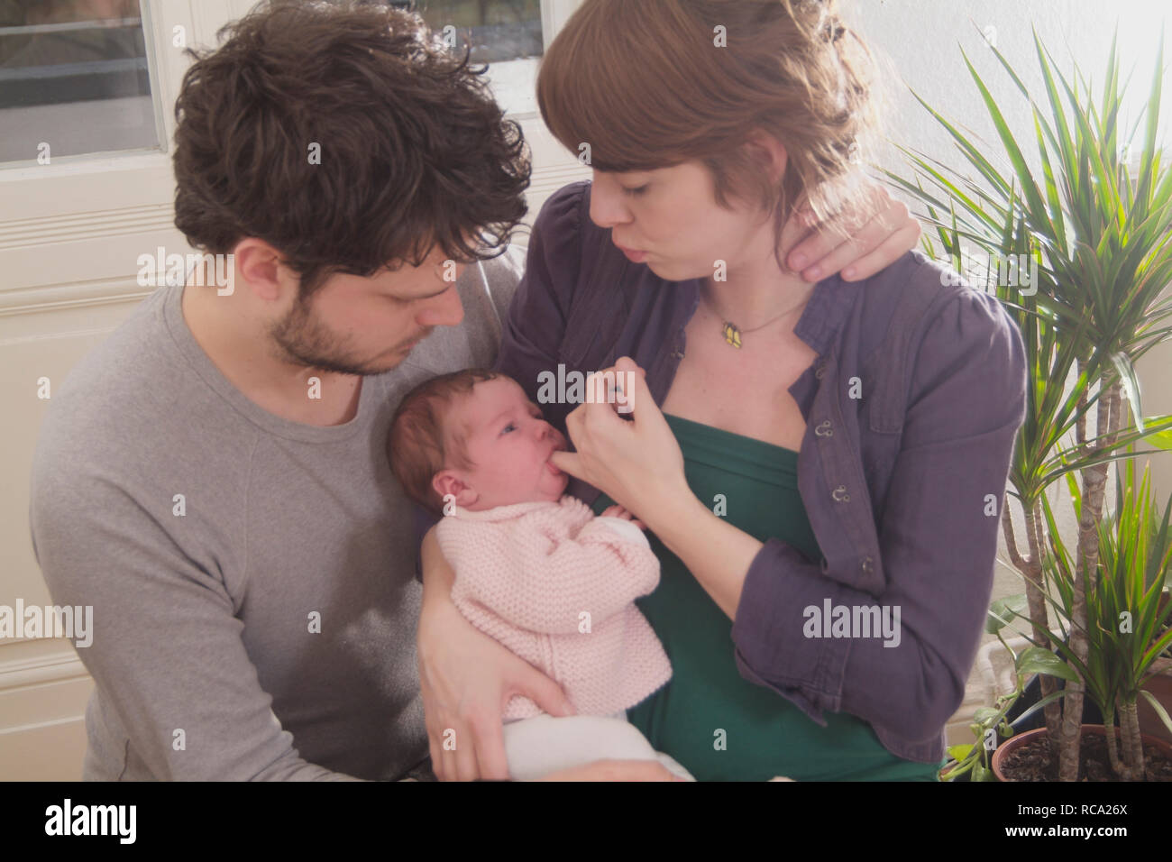 Junge Eltern halten ihre neugeborene Tochter im Arm, das Kind ist 12 Tage alt | young parents holding her new born baby in her arms - the baby ist 12  Stock Photo