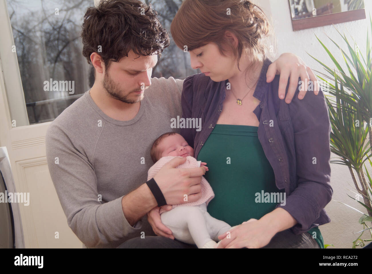 Junge Eltern halten ihre neugeborene Tochter im Arm, das Kind ist 12 Tage alt | young parents holding her new born baby in her arms - the baby ist 12 Stock Photo