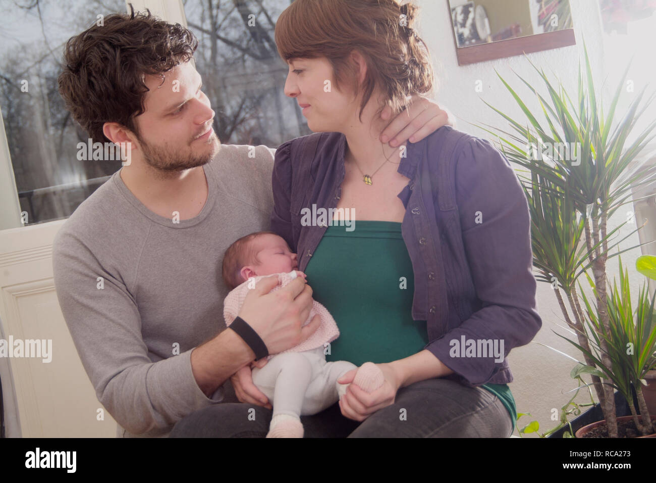 Junge Eltern halten ihre neugeborene Tochter im Arm, das Kind ist 12 Tage alt | young parents holding her new born baby in her arms - the baby ist 12 Stock Photo