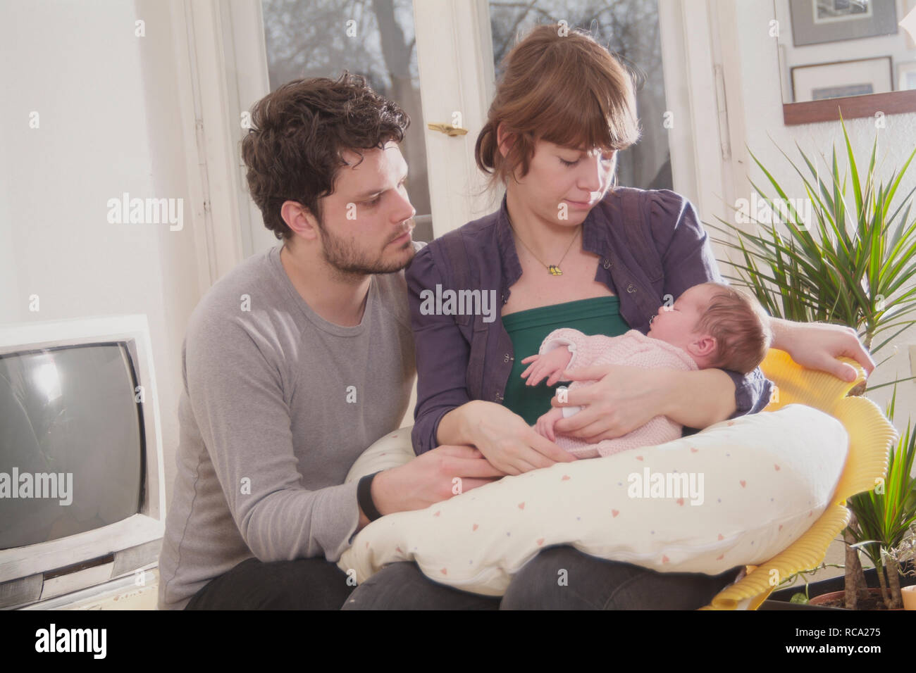 Junge Eltern halten ihre neugeborene Tochter im Arm, das Kind ist 12 Tage alt | young parents holding her new born baby in her arms - the baby ist 12 Stock Photo