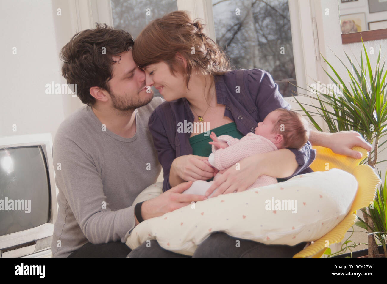 Junge Eltern halten ihre neugeborene Tochter im Arm, das Kind ist 12 Tage alt | young parents holding her new born baby in her arms - the baby ist 12 Stock Photo