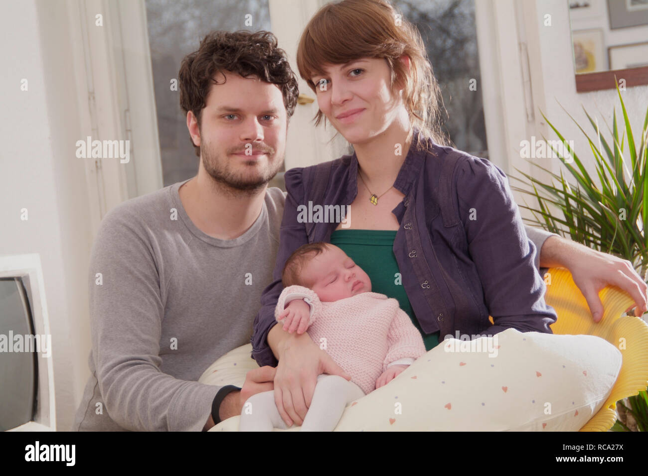 Junge Eltern halten ihre neugeborene Tochter im Arm, das Kind ist 12 Tage alt | young parents holding her new born baby in her arms - the baby ist 12 Stock Photo