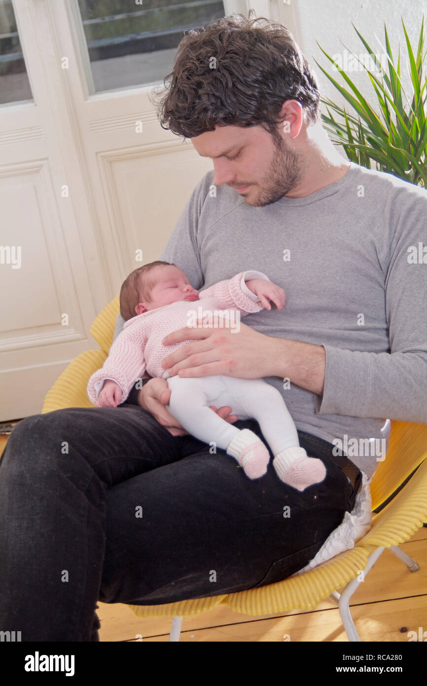 Junger hält seine neugeborene Tochter im Arm, das Kind ist 12 Tage alt | young father holding his new born baby in his arms - the baby ist 12 days old Stock Photo