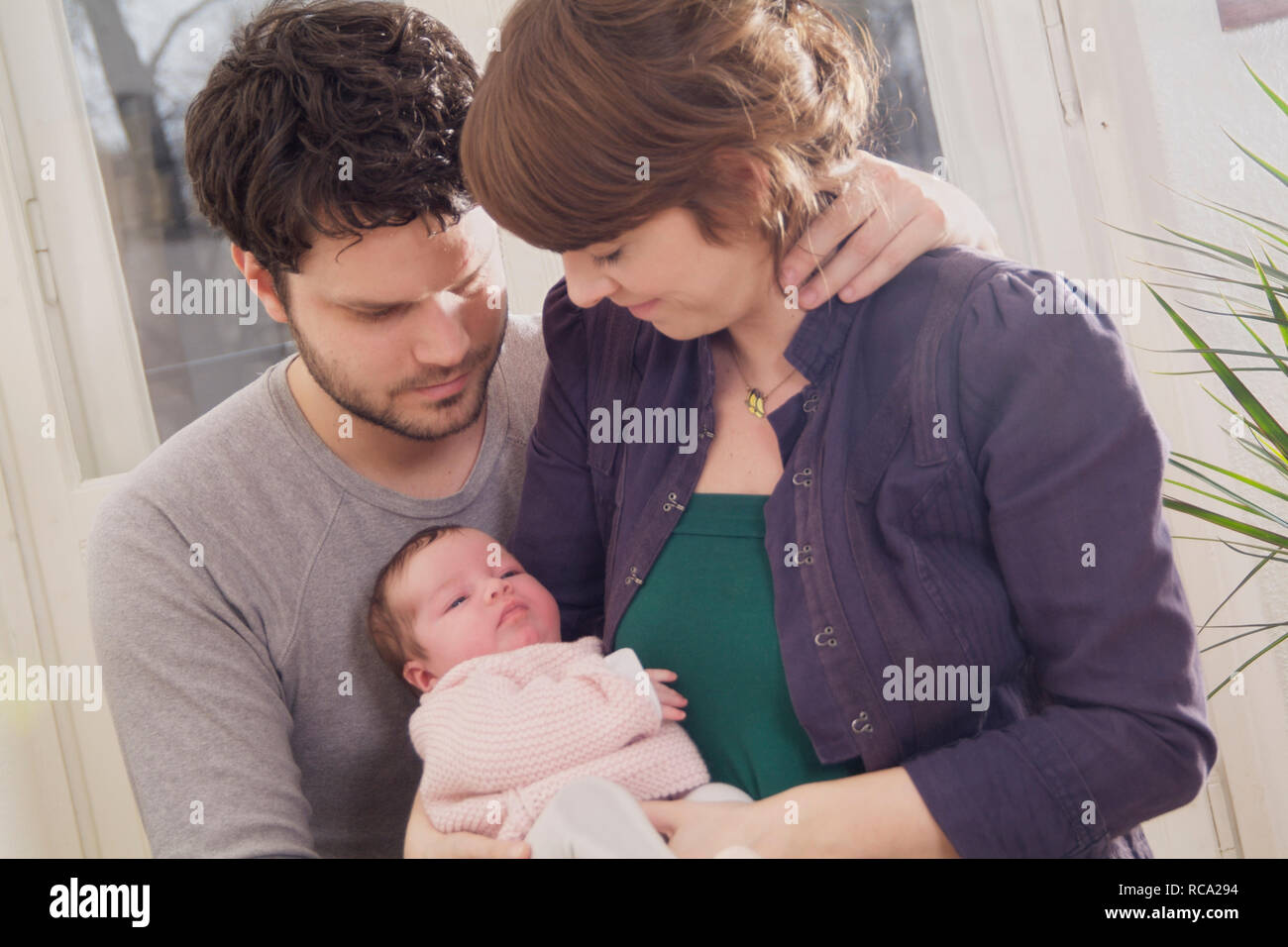 Junge Eltern halten ihre neugeborene Tochter im Arm, das Kind ist 12 Tage alt | young parents holding her new born baby in her arms - the baby ist 12 Stock Photo