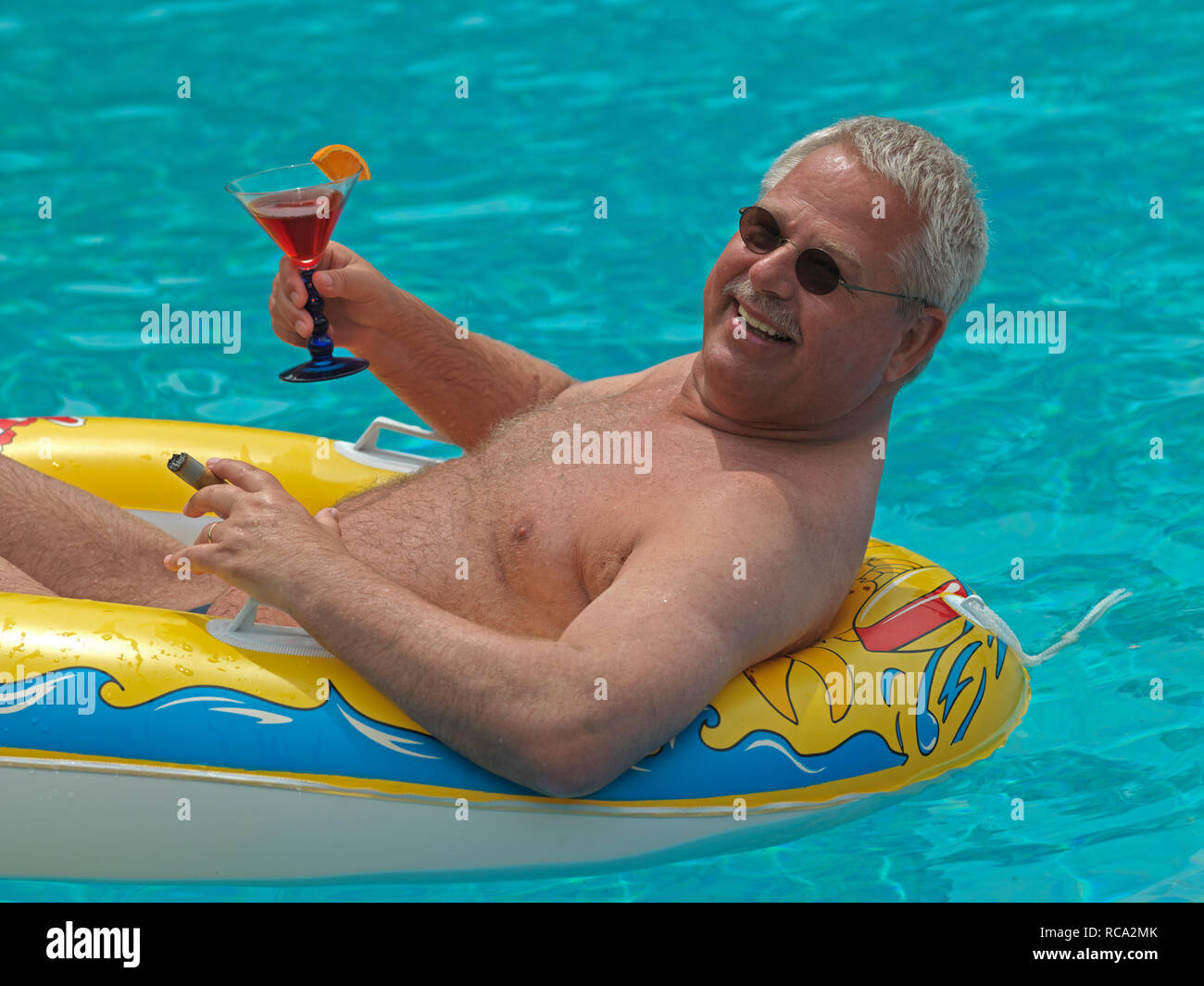 älterer Mann genießt das Leben im kleinen Schlauchboot im Swimmingpool | elderly man with a rubber dinghy in the swimming-pool Stock Photo