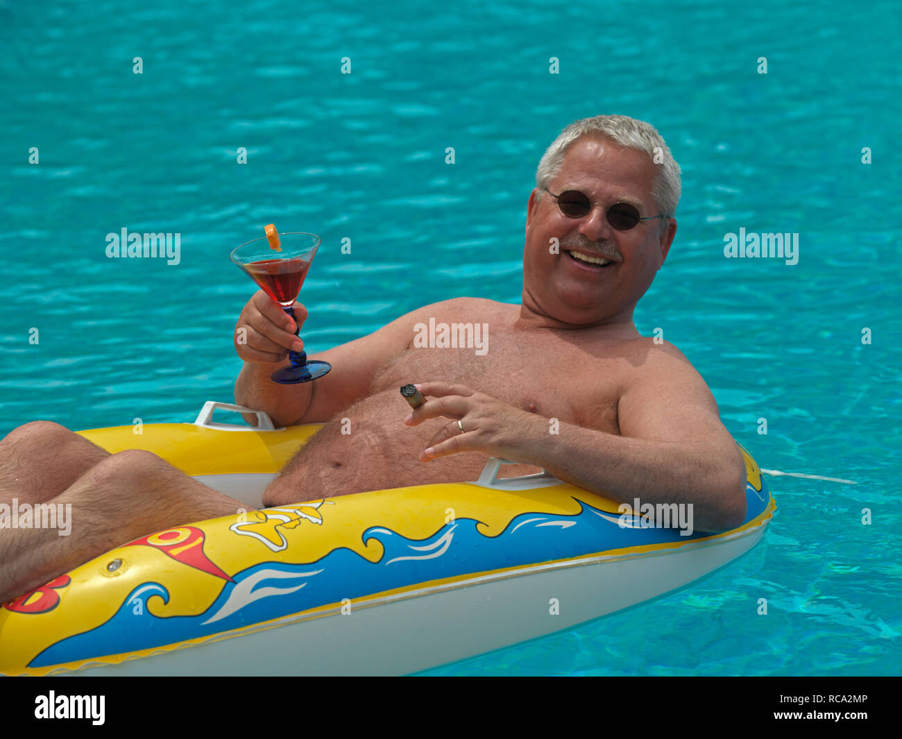 älterer Mann genießt das Leben im kleinen Schlauchboot im Swimmingpool | elderly man with a rubber dinghy in the swimming-pool Stock Photo