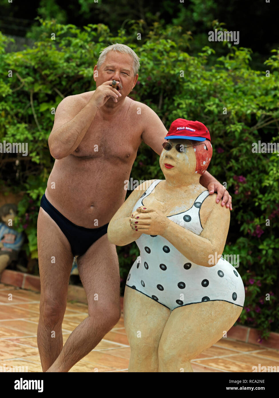 älterer Mann in Badehose steht neben Skulptur von Christel Lechner | elderly man in bathing-trunks standing beside a sculpture from Christel Lechner Stock Photo