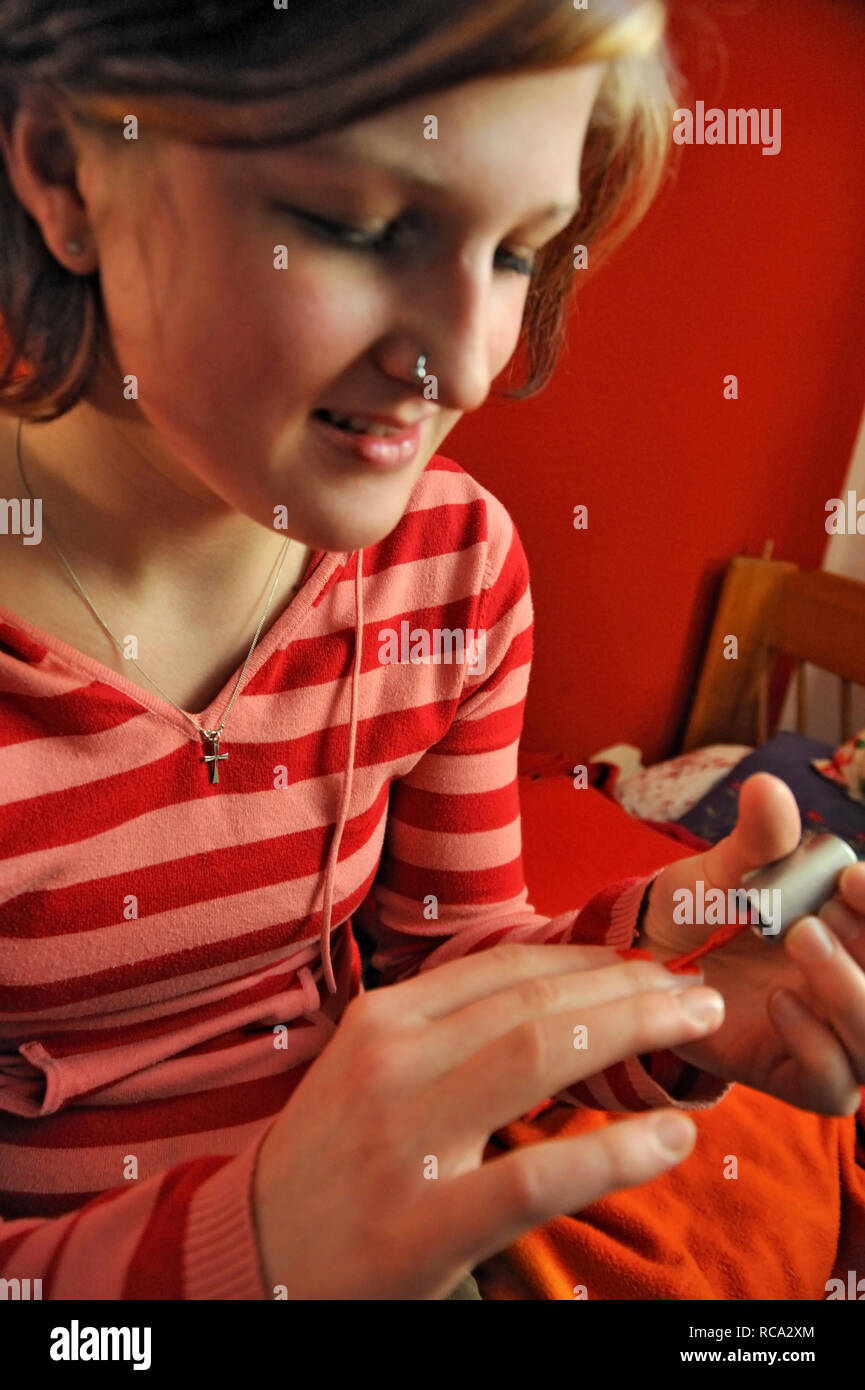 junge Frau lackiert sich die Nägel | young woman varnishing her fingernails Stock Photo
