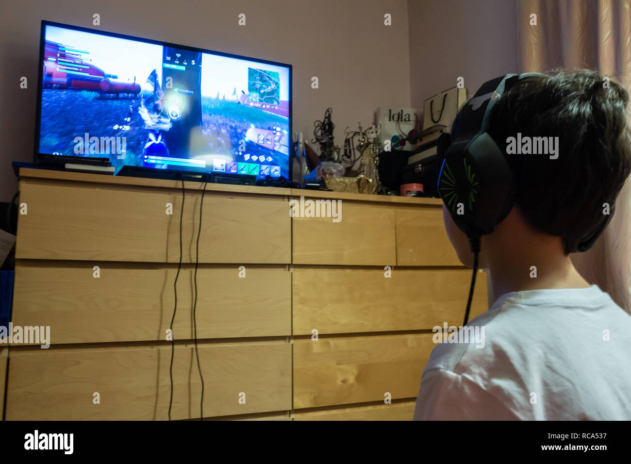 A young boy plays the computer game Fortnite on a games console in a bedroom Stock Photo