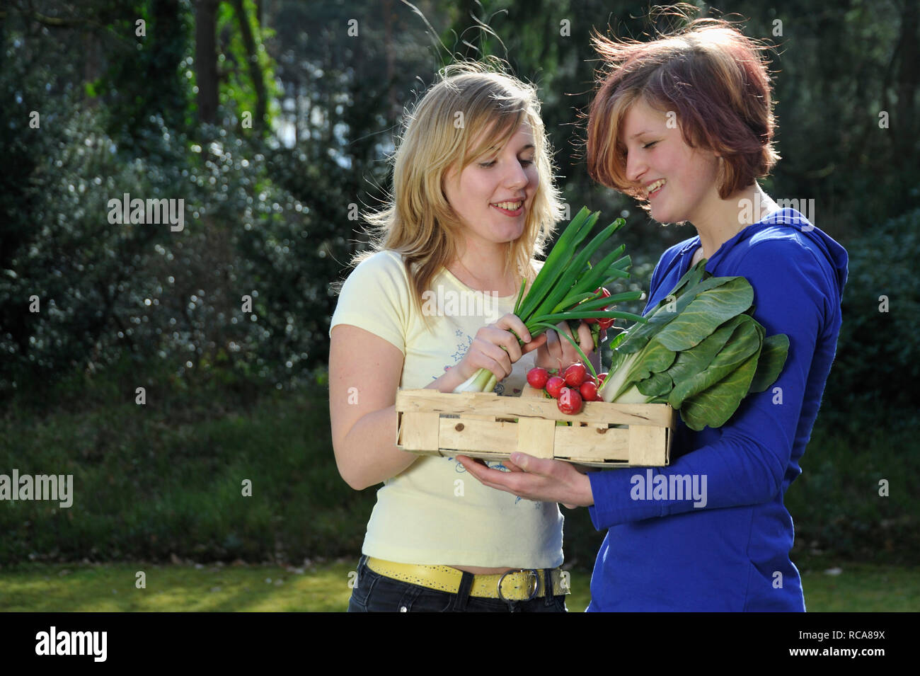 zwei jungendliche Frauen mit Gemüsekorb im Arm - junges Gemüse | two young women with vegetable basket Stock Photo