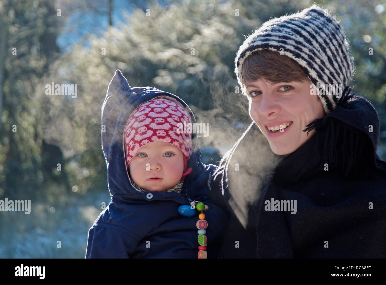 Mutter mit Baby im Arm, draußen Winter | mother carrying her baby on the arm, outside winter Stock Photo
