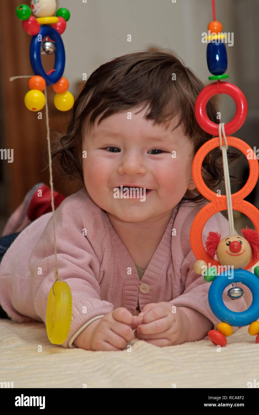 Baby im Zimmer liegt auf dem Boden, Spielzeug | baby lying in a room on the floor, playing with toys Stock Photo