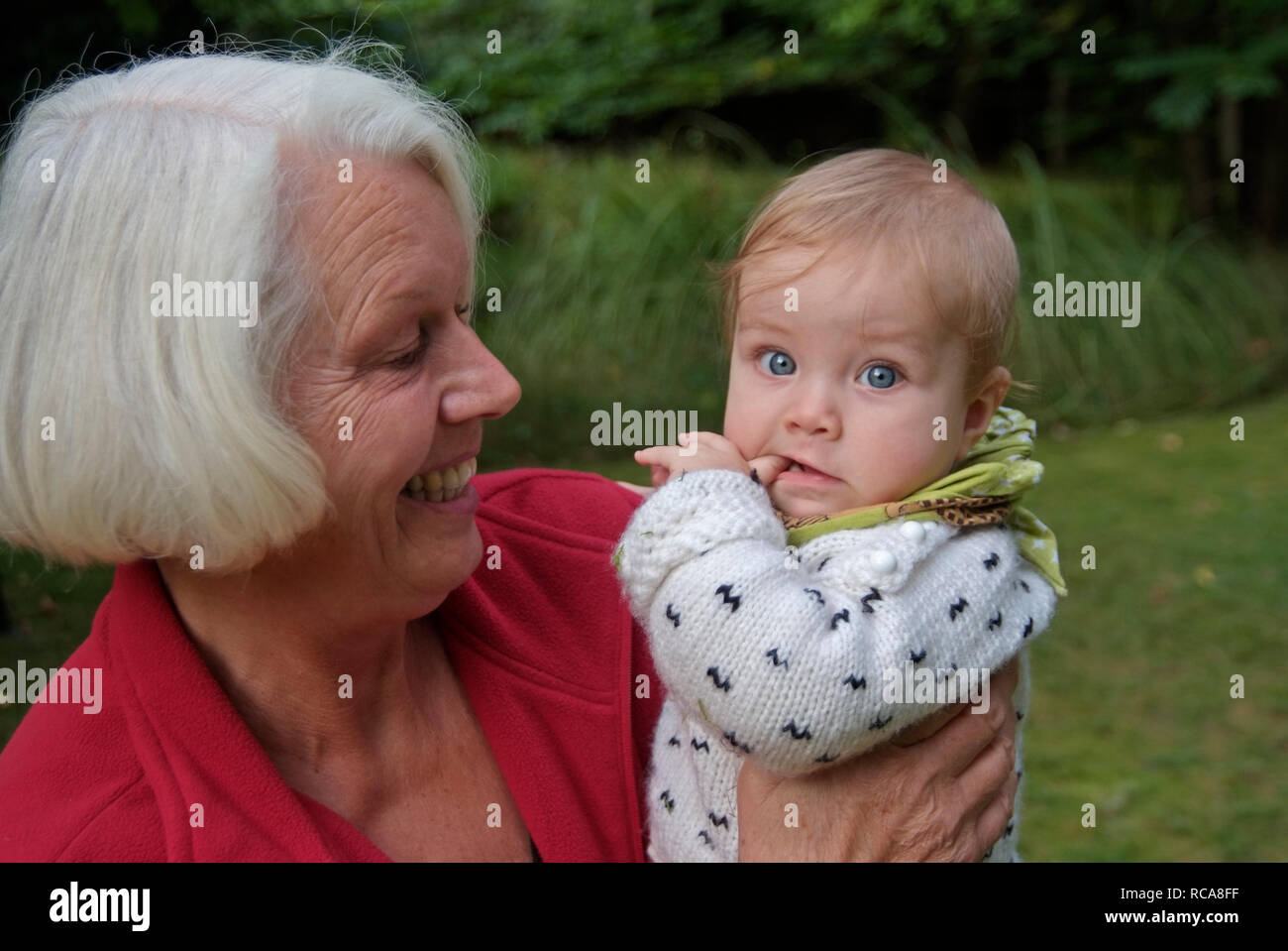 Oma hat Enkelkind im Arm | Grandmother carries her granddaughter on her arm Stock Photo