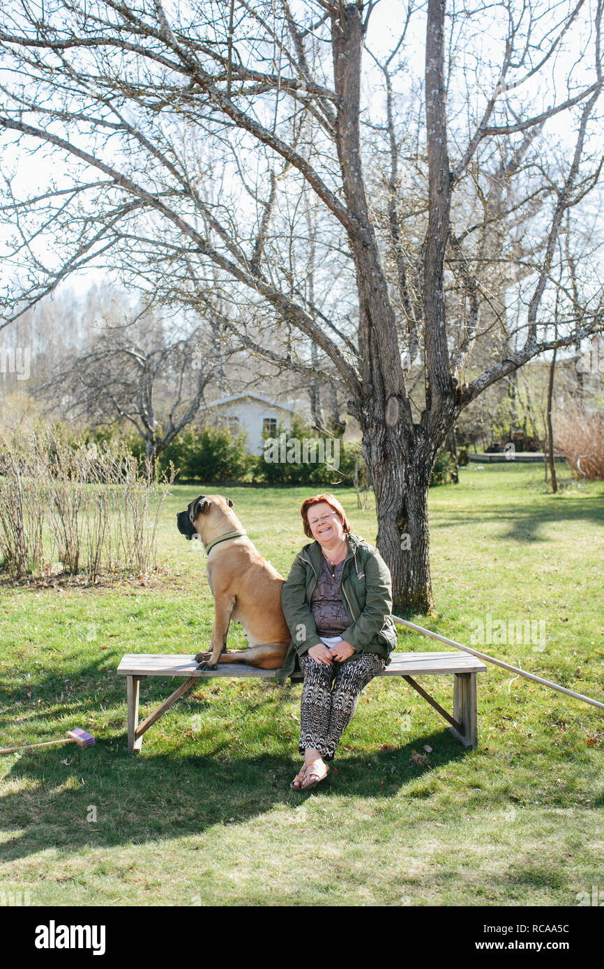 Mature woman and dog sitting on bench Stock Photo - Alamy